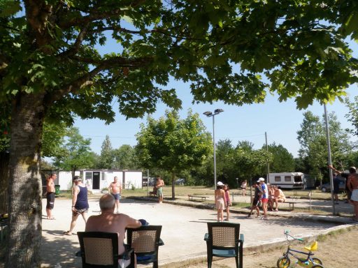 Un terrain de pétanque animé par des joueurs sous un ciel ensoleillé.