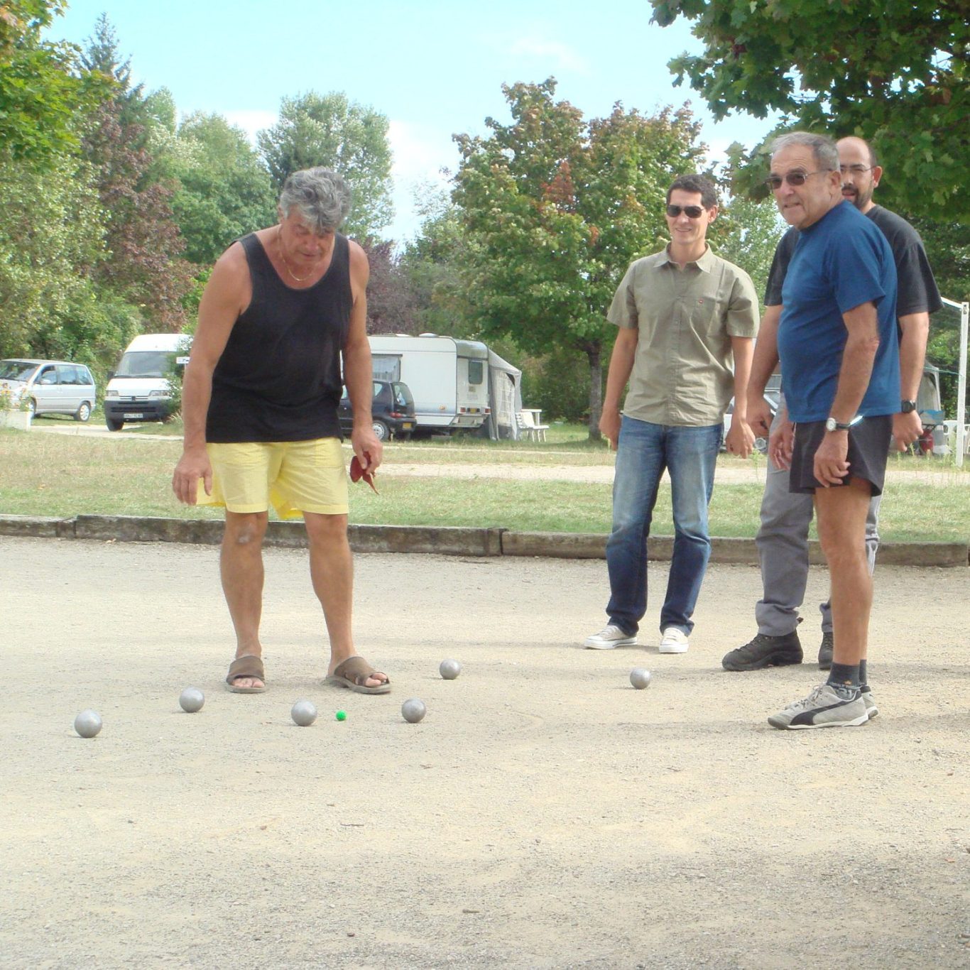 Des hommes jouant à la pétanque dans un parc, concentrés sur la partie.